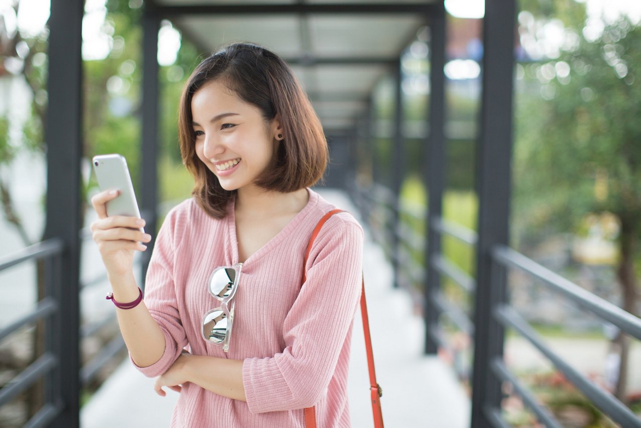 Asia woman using with smart phone in the street in a sunny summer day