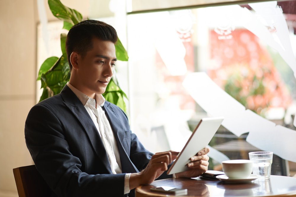 A woman tallking to someone on the phone and smiling as she looks at her laptop screen