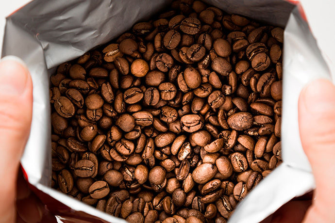 Top view of darkly roasted coffee beans in an open bag 