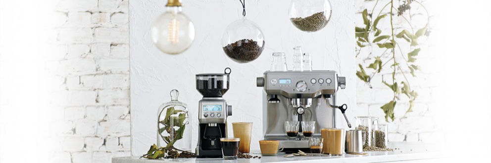 커피 그라인더와 에스프레소 머신이 여러 도구들과 함께 테이블위에 놓여있다.