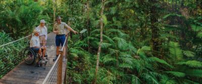  A woman and a man in a wheelchair listen to a guide on the Skyrail Rainforest Cableway