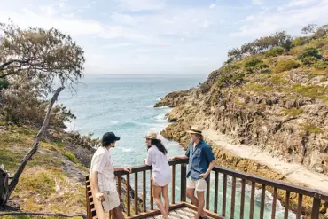 A group of friends on a beach boardwalk looking out at the view