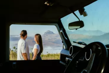 Couple stand outside their 4WD admiring country views