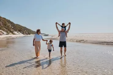 Parents and two kids walking along the beach together Parents and two kids walking along the beach together