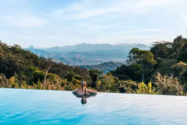 Lady enjoying a swim in an infinity pool, within a rainforest setting at O'Reilly's Rainforest Retreat