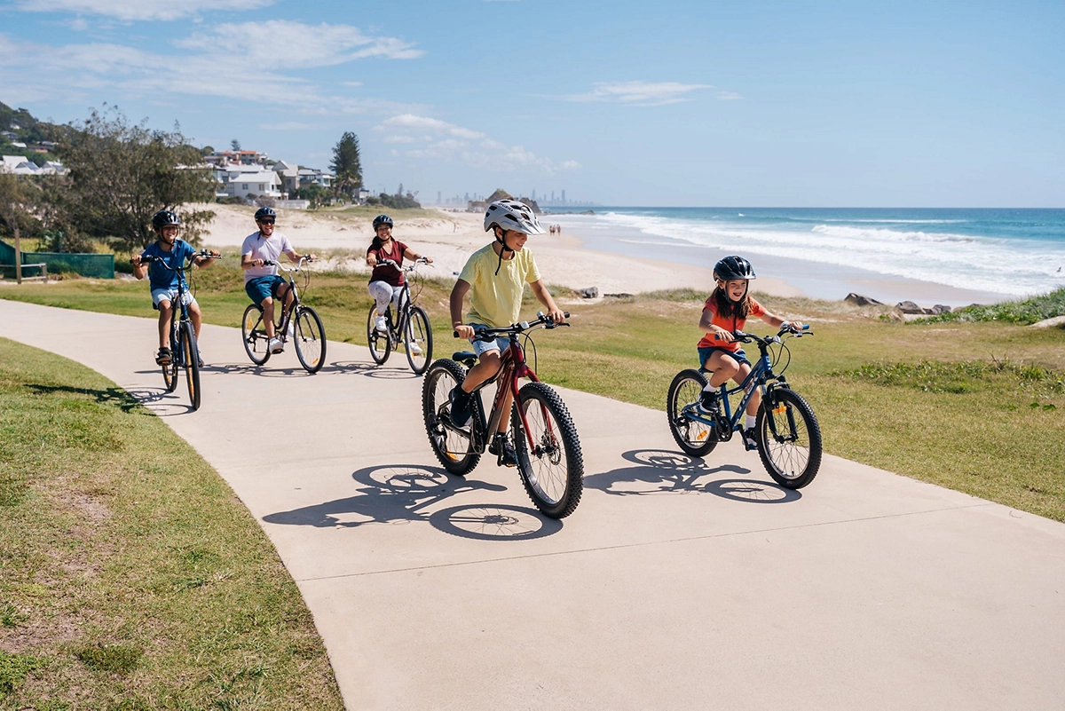 Family cycling along the beachfront pathway at Tugun Beach, Gold Coast Family cycling along the beachfront pathway at Tugun Beach, Gold Coast