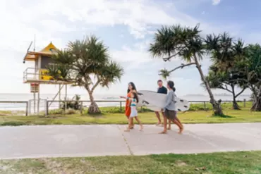 A family, carrying surf boards, walks along a coastal path at Tugun Beach A family, carrying surf boards, walks along a coastal path at Tugun Beach