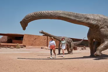 Two women walk under replica dinosaurs outside Australian Age of Dinosaurs museum in Winton Two women walk under replica dinosaurs outside Australian Age of Dinosaurs museum in Winton