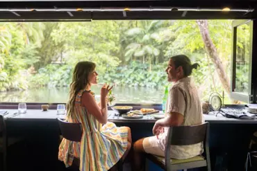 A man and woman eat lunch at Spirit House set amongst lush tropical rainforest 