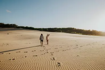 Couple walking across the sand dunes of Carlo Sand Blow near Rainbow Beach | backpackers guide Sunshine Coast Couple walking across the sand dunes of Carlo Sand Blow near Rainbow Beach | backpackers guide Sunshine Coast