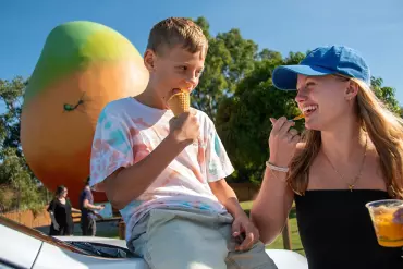 Kids in front of the Big Mango enjoying a mango fruit treat in Bowen Kids in front of the Big Mango enjoying a mango fruit treat in Bowen