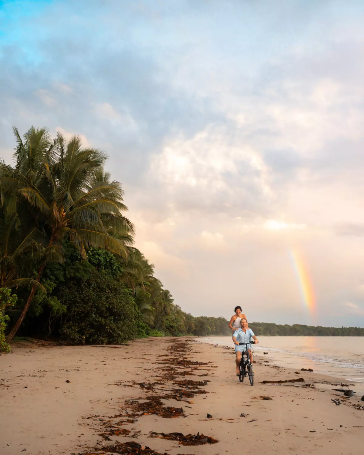 Couple riding a bike on Four Mile Beach, Port Douglas | beautiful beaches Queensland Couple riding a bike on Four Mile Beach, Port Douglas | beautiful beaches Queensland