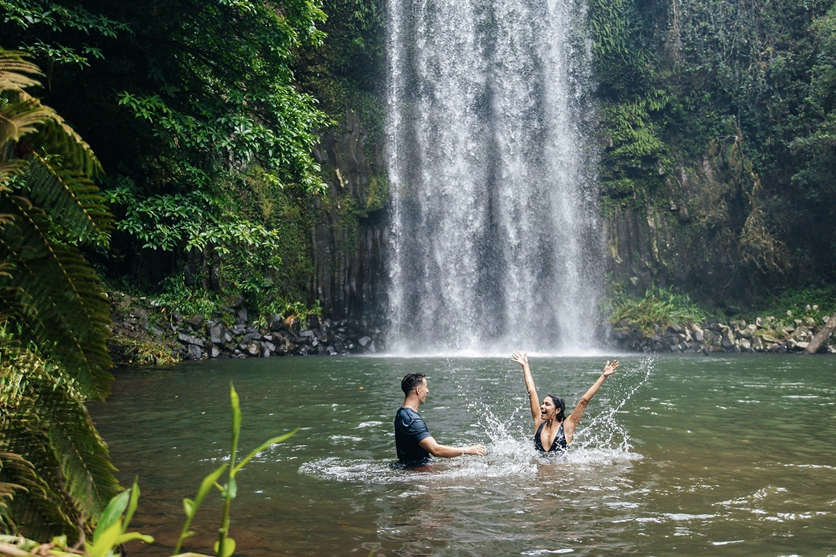 A couple splashing in the water at the base of a waterfall A couple splashing in the water at the base of a waterfall