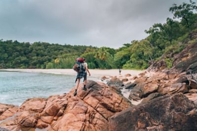 Hiker on rocks with a backpack on a beach