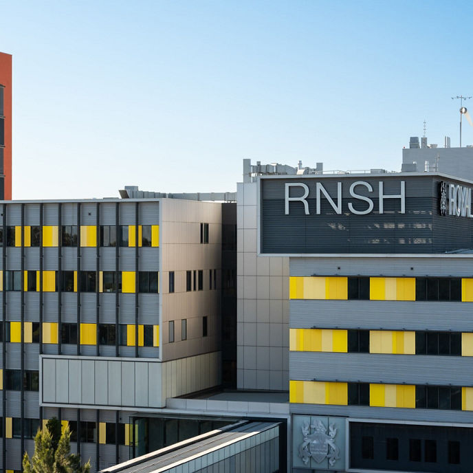 Royal North Shore Hospital exterior with a “RNSH” sign on the front and yellow panels placed intermittently across the building 