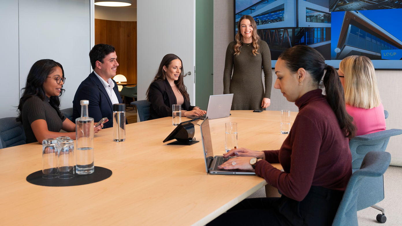 Dexus employees in a meeting with a woman standing and presenting 