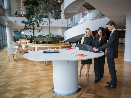 Three people in a stand-up meeting in a spacious office 