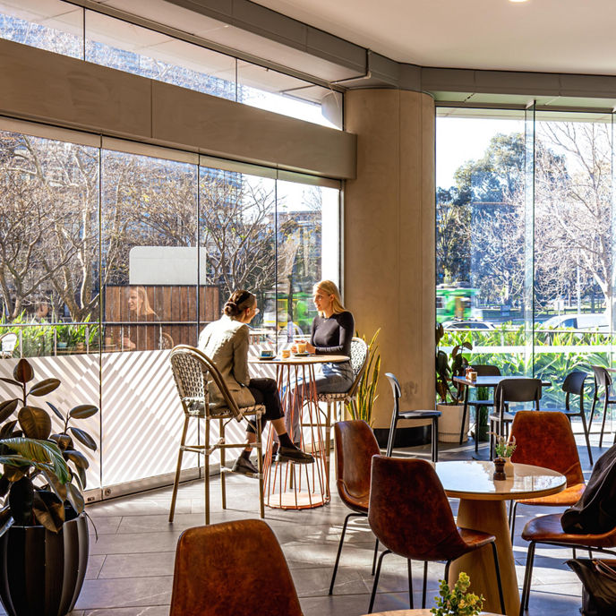 Interior image of 636 St Kilda Road Melbourne cafe lobby with two women seated having a conversation over coffee 