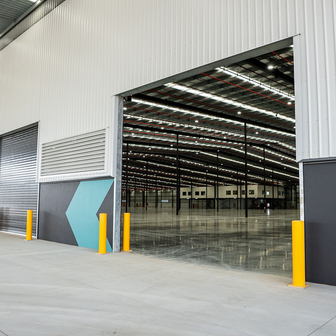 Photo of open roller shutter looking inside to a large warehouse
