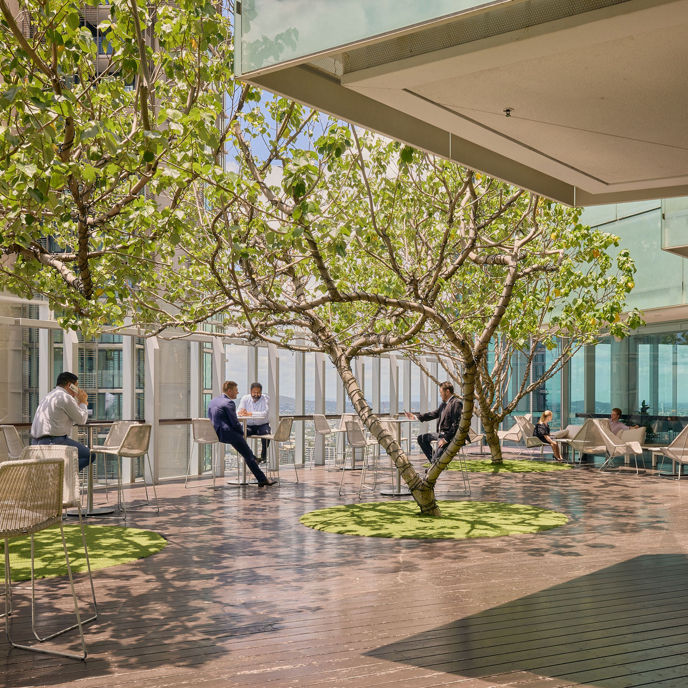 Exterior image of 480 Queen Street Brisbane rooftop terrace with chairs and tables, trees, and people sitting