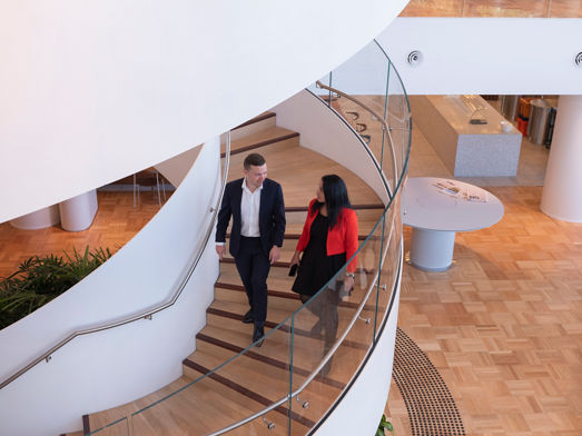 Two people walking down a set of spiral stairs in an office 