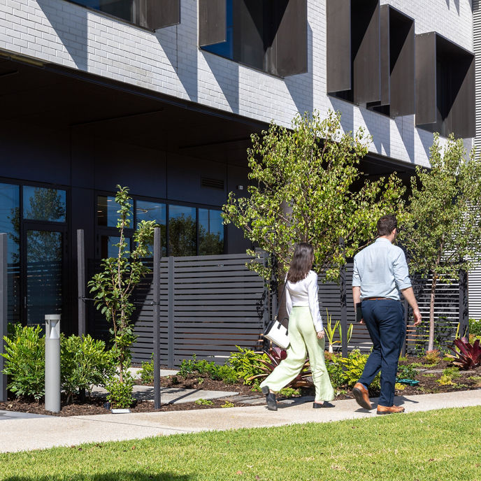 An outdoor garden at Cockburn Mental Health Clinic with two people walking along a path 