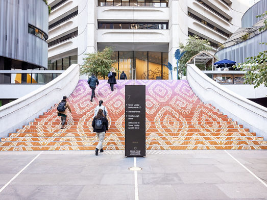A set of stairs with First Nations artwork on them and totem signage in front