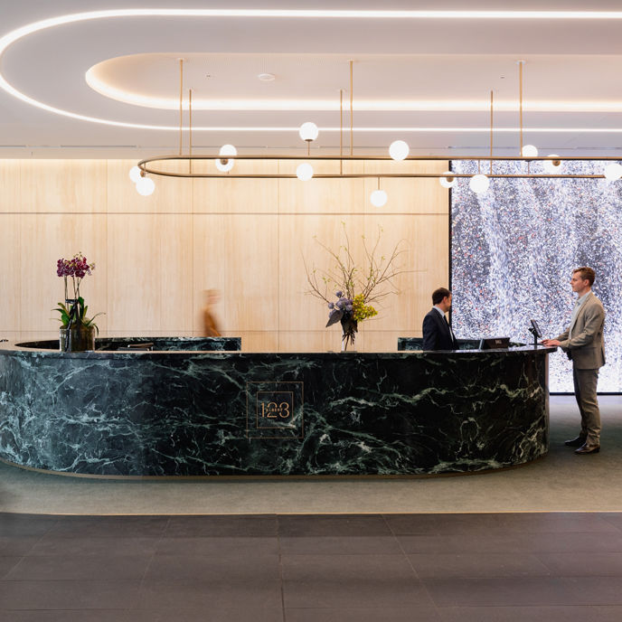 A concierge and customer at a marble front desk at 123 Albert Street