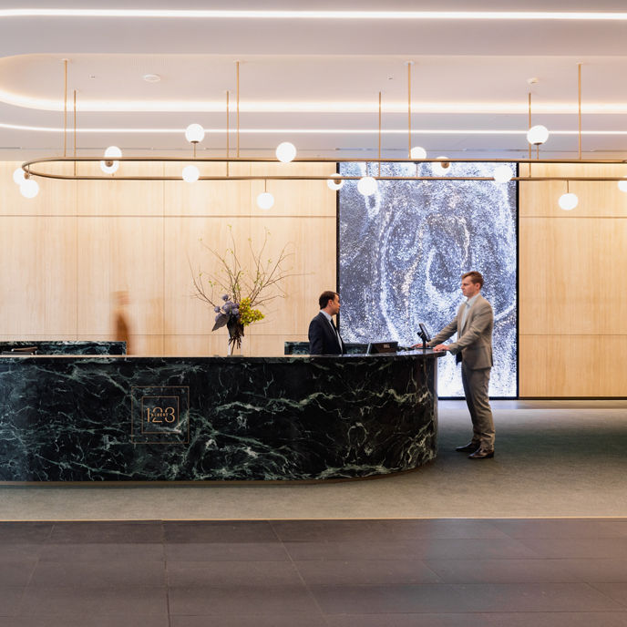 A concierge and customer at a marble lobby desk at 123 Albert Street