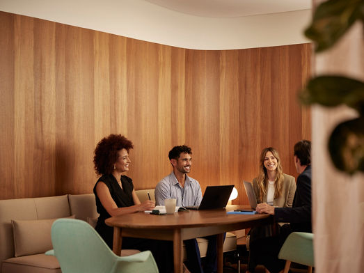 A group of four office workers collaborating in a casual office space
