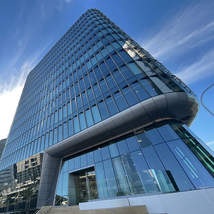 Looking up at the Australian Bragg Centre with a blue sky and clouds in the background 