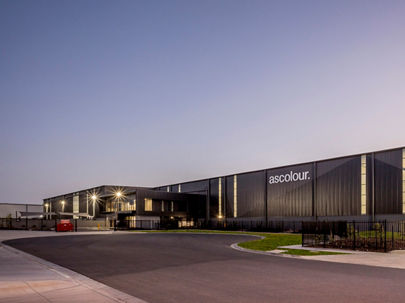 Exterior image of large black industrial warehouse from street level at dusk 