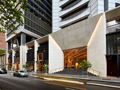 A white, square frontage to a building with a cars driving past 