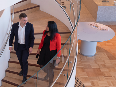 Two people walking down a spiral staircase in an office 
