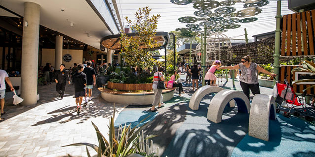 Kids playing on a playground outside a retail centre 