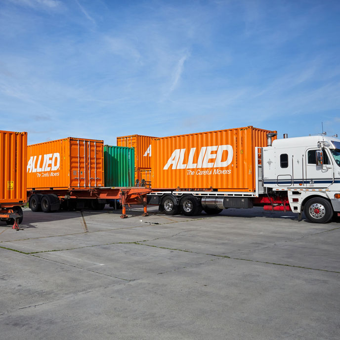 Image of orange Allied branded shipping containers on trucks