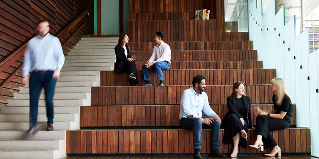 People sat on stairs in an office engaged in conversation 