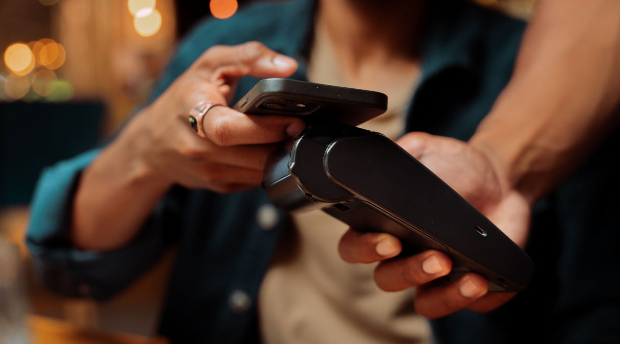 African American customer paying with cellular device and card machine at restaurant. High quality photo