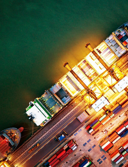 Top view of international port with Crane loading containers in import export business logistics at night.