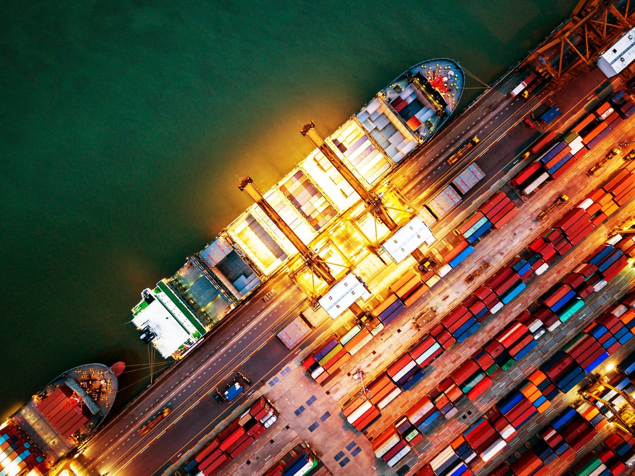 Top view of international port with Crane loading containers in import export business logistics at night.