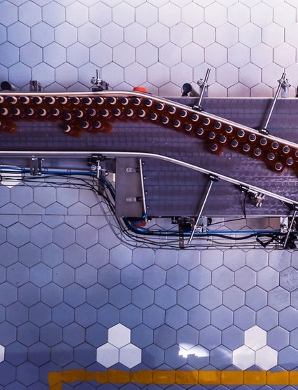Industry, Business, Factory, Bottling Plant - Bottles Filled with Fresh Drink Moving on a Conveyor Belt to the Packaging Section of a Factory.