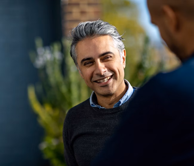 Cheerful man in his 40s having informal meeting with colleagues on urban rooftop discussing project, togetherness, teamwork, confidence