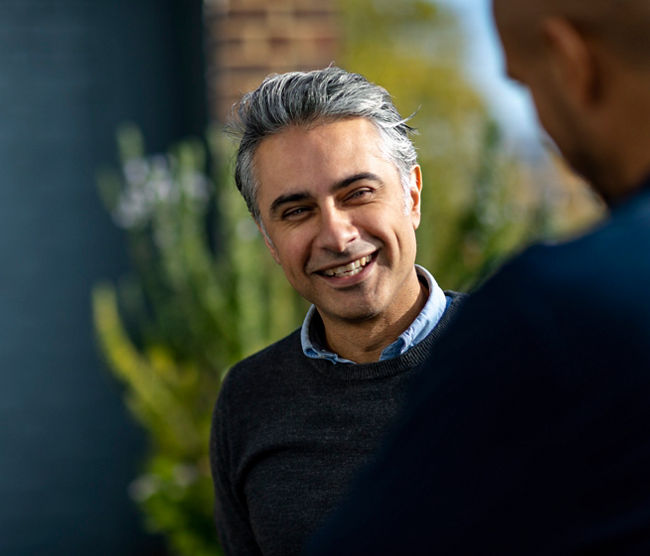 Cheerful man in his 40s having informal meeting with colleagues on urban rooftop discussing project, togetherness, teamwork, confidence