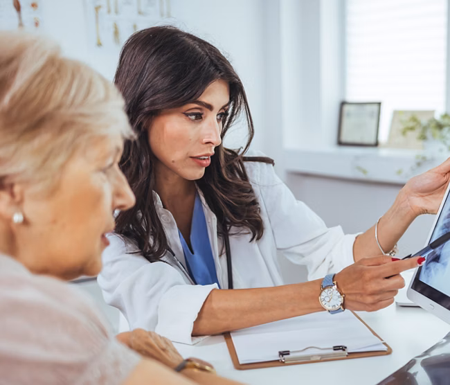 Doctor shows results to old patient x-ray of the lungs, smoking cigarettes problem. Doctor explaining lungs x-ray on Tablet PC screen to young patient. Doctor showing female patient x-ray shot in clinic office. Coronavirus chest X-ray.