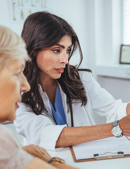 Doctor shows results to old patient x-ray of the lungs, smoking cigarettes problem. Doctor explaining lungs x-ray on Tablet PC screen to young patient. Doctor showing female patient x-ray shot in clinic office. Coronavirus chest X-ray.