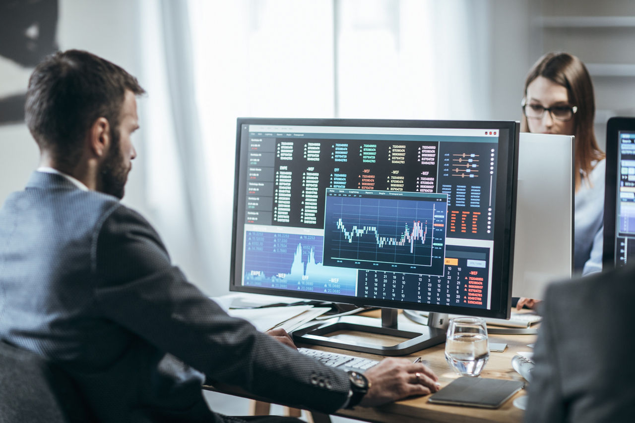 Businesspeople working with finance forecasts on their computers.