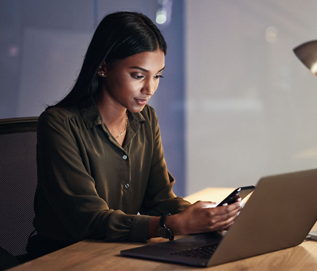 Laptop, phone and business woman on coding, software development and programming script for cybersecurity. Night, mobile research and multimedia programmer or IT person on computer with data analysis.