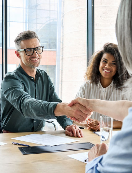 Happy businessman and businesswoman shaking hands at group board meeting. Professional business executive leaders making handshake agreement successful company trade partnership handshake concept.