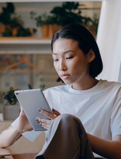 Woman on her tablet with a computer in the background