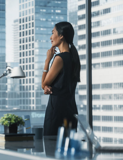 Successful Businesswoman in Stylish Dress Working on Laptop, Looking out of the Window at Big City. Confident Female CEO Analyze Financial Projects. Manager at Work Planning Marketing Campaign.